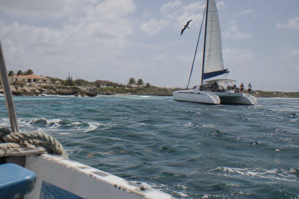 A catamaran under sail on calm water off the west coast of Aruba